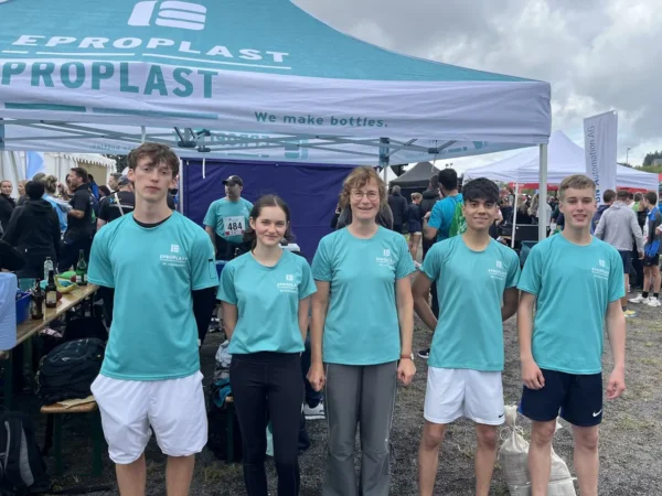 Vier Jugendliche und eine erwachsene Begleitperson in EPROPLAST-Shirts stehen beim Südthüringer Firmenlauf in Oberhof vor einem EPROPLAST-Pavillon.