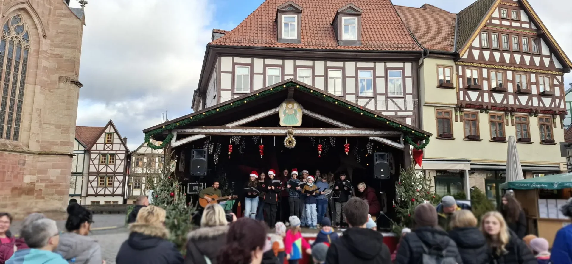 Der Schulchor der Regelschule Schmalkalden steht auf einer weihnachtlich geschmückten Bühne und singt vor Publikum auf dem Schmalkalder Weihnachtsmarkt.