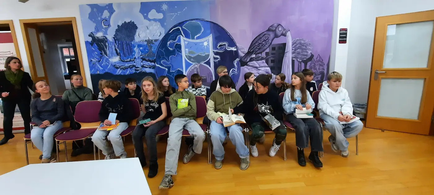 Schülerinnen und Schüler der Klassenstufe 6 sitzen nebeneinander und hören beim Lesewettbewerb aufmerksam zu. Einige halten Bücher in den Händen.