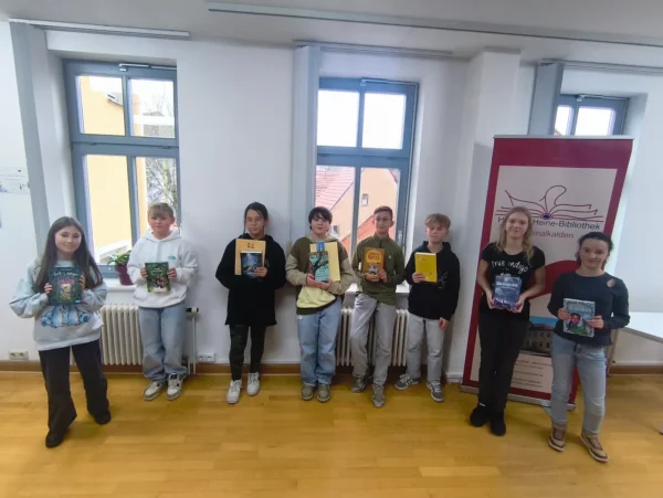 Acht Schülerinnen und Schüler der Klassenstufe 6 stehen nebeneinander und halten Bücher beim Lesewettbewerb der Regelschule Schmalkalden.