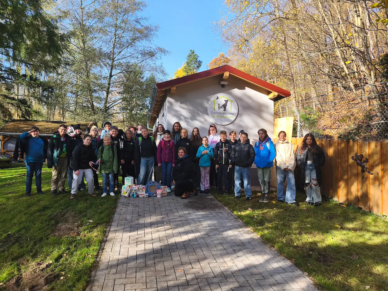 Die Klasse 6c steht mit ihren Begleitern vor dem Gebäude des Tierschutzvereins Schmalkalden. Im Vordergrund liegen gesammelte Sachspenden für Tiere.
